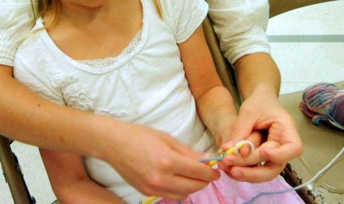 Teaching Your Child To Work With Her Hands: 4 Benefits of Early Training. showing a child how to knit, casting on stitches