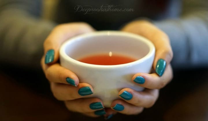 10 Tried & True Reasons Raspberry Leaf Is Great For All Women. A woman holding a cup of red raspberry tea.
