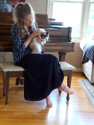 A woman holding cat at grand piano