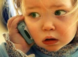 a small child holding cell phone to ear