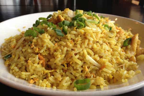 Turmeric fried rice with golden paste added on a plate with green onions