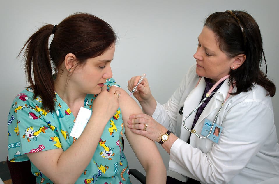 22,000 US Nurses Refuse Flu Vaccines At Expense Of Career. A doctor giving shot to a concerned woman, 