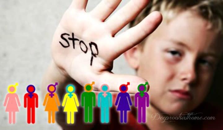 Photo of a distressed young boy holding up his hand with the word STOP written on his palm.