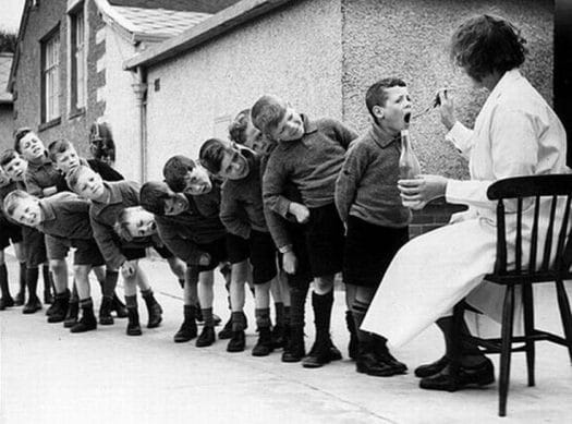 Fish or Cold Liver Oil Can Help Brain Processing Disorders, ADHD. Old photo of young children at a school in Europe lined up, taking CLO on spoon, 