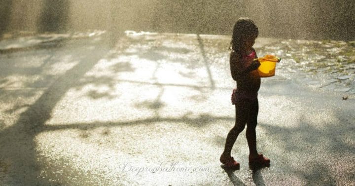 It's Not Dangerous For Kids To Be Bored Sometimes. Young child in a swimsuit entertained with only the rain and a bucket