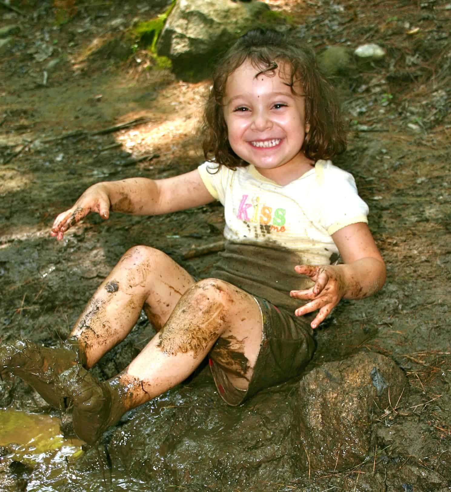 happy little girl playing hard at the edge of a creek